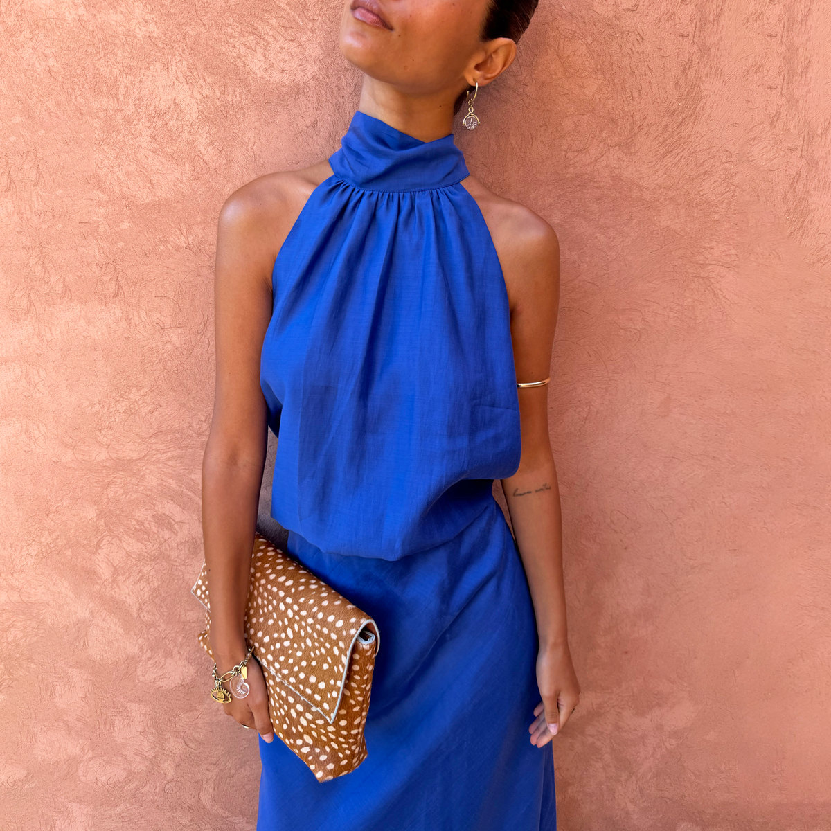 Cobalt Billie Top with a high gathered neckline and scarf detail for multi-wear styling against a terracotta wall.