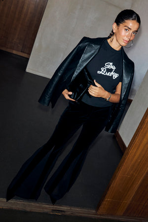 Black Leather Blazer draped over a graphic t-shirt and black flared trousers for a London look.