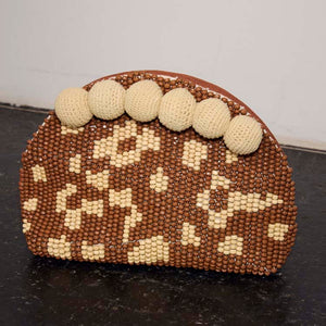 Jaden Beaded Clutch Bag featuring brown and cream patterned beads and statement cream crochet pom-poms.