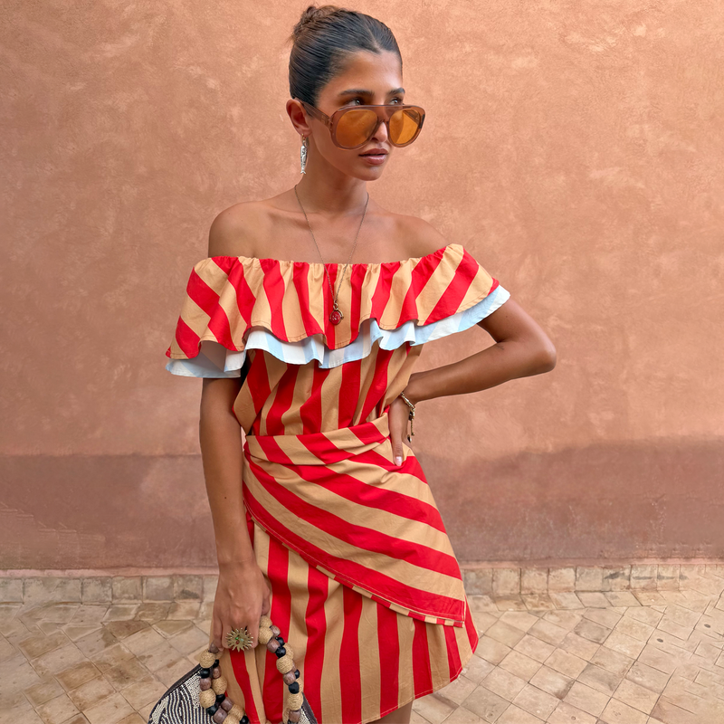 Sciarpa Tomato Stripe a righe rosse e color cammello indossata come top multi-wear a spalle scoperte.