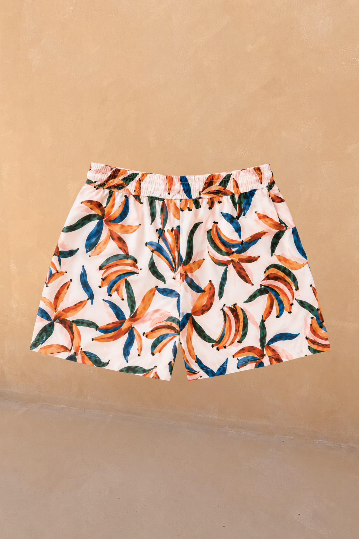 Boy's Banana Print Swim Shorts in cream with orange and blue banana clusters and an elasticated waistband.