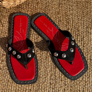 Black Leather Stud Sandals with a square toe, silver hardware and a red footbed on a woven mat.