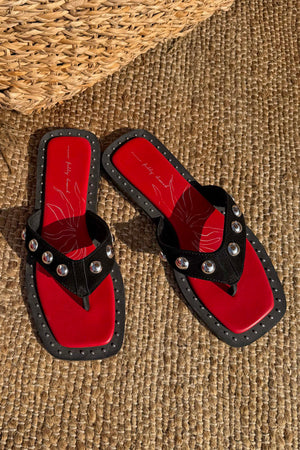 Black Leather Stud Sandals with silver studs and a red square-toe footbed on a woven mat.