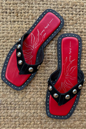 Black Leather Stud Sandals featuring a square toe, silver studs and a red footbed, displayed on a woven mat.