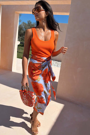 Blue Poppy Jaspre Skirt with an orange floral print on light blue fabric and iconic wrap tie fastening.