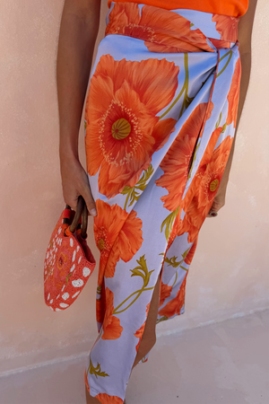 Blue Poppy Jaspre Skirt featuring large orange flowers on a light blue base with an iconic wrap tie fastening.