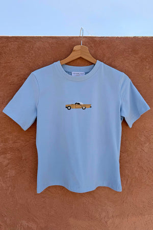 Cadillac Baby T-Shirt in blue stretch cotton with a retro car motif hanging on a wooden hanger.
