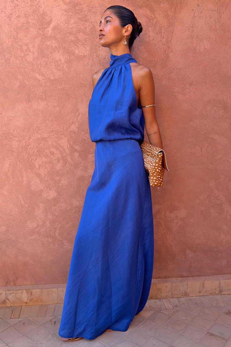 Cobalt Daphne Skirt co-ord with a matching high-neck top and leopard print clutch against a terracotta wall.