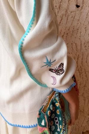 Cream Celestial Martha Cardigan sleeve featuring embroidered cosmic motifs and blue blanket stitch trim.