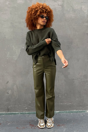 Khaki Vegan Leather Trousers paired with a dark green jumper and leopard print trainers.