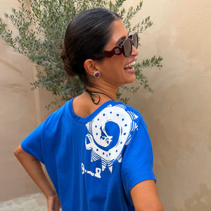 Occhiali da sole Red Wiggle Arm in acetato rosso indossati da una modella con t-shirt blu.