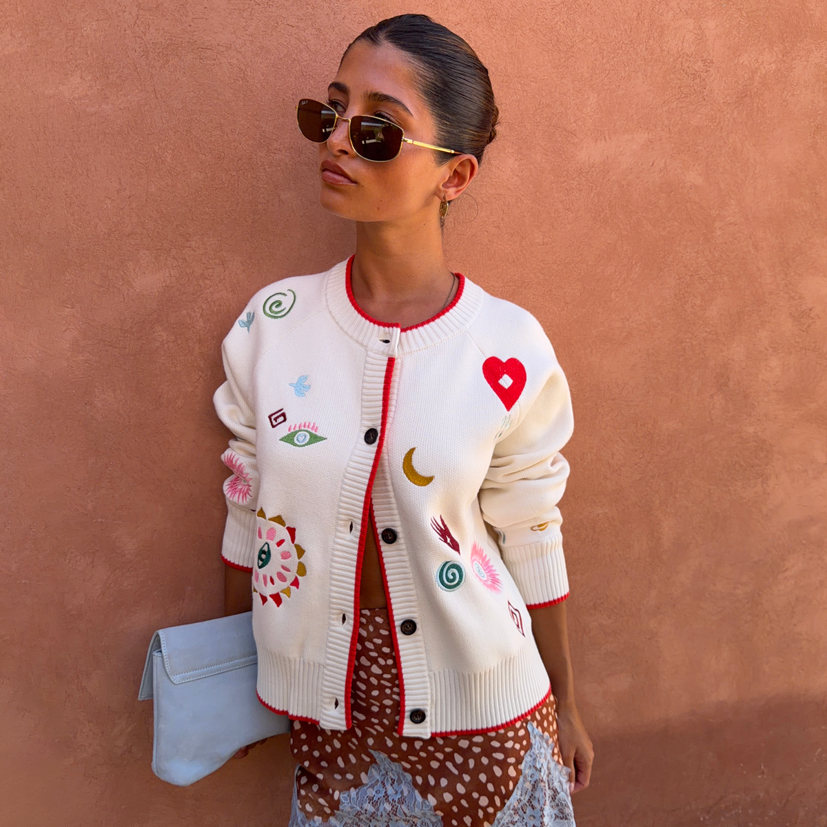 Cardigan bianco Morocco Charms Cheryl con ricami vivaci e bordi rossi indossato da una modella.