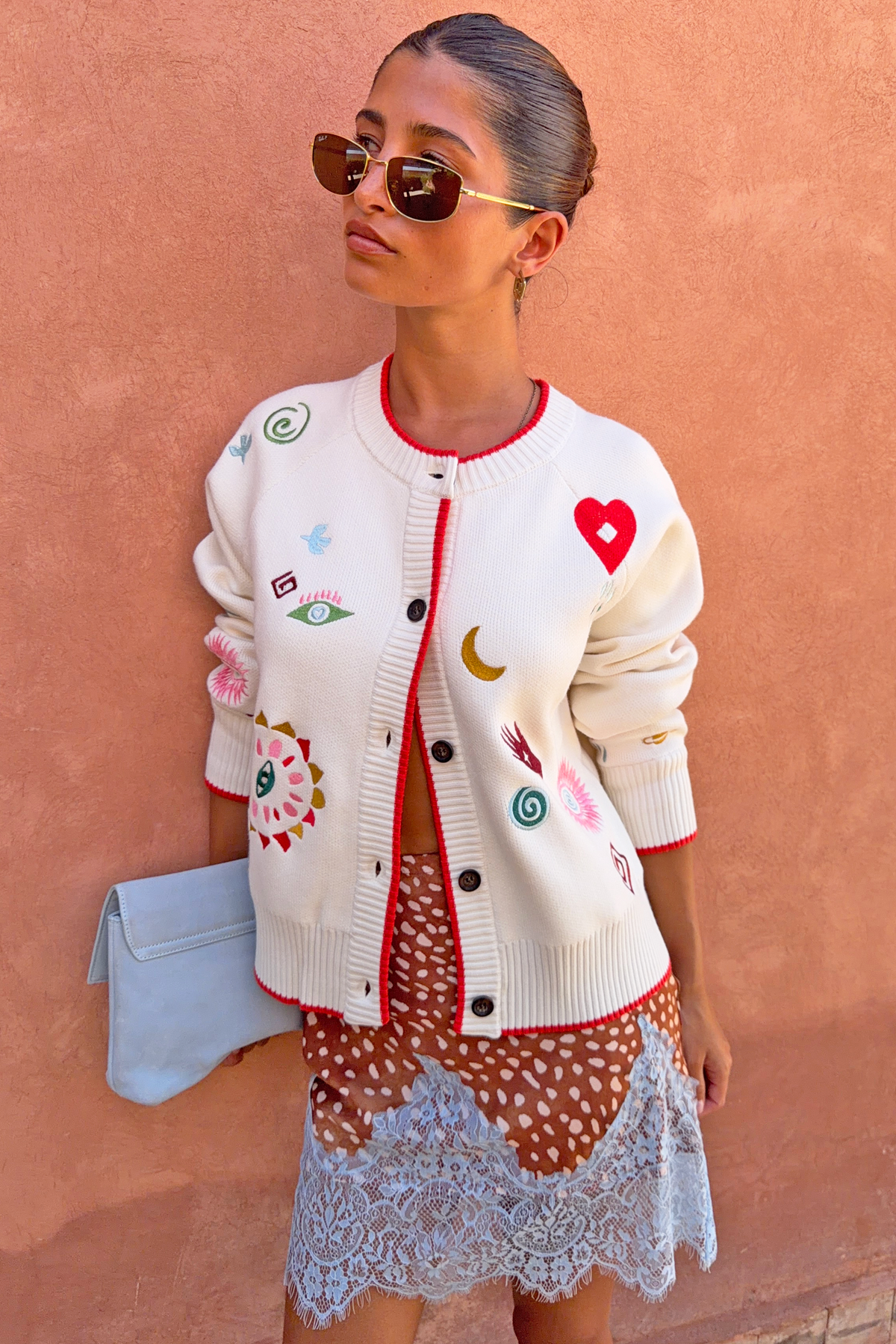 Cardigan bianco Morocco Charms con ricami colorati, indossato con gonna in pizzo da una modella alta 162 cm.