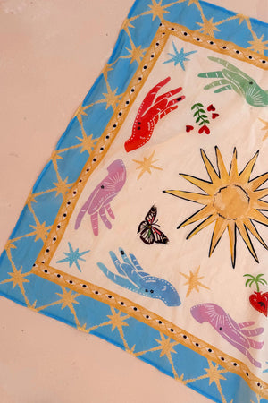 Celestial Bandana featuring a blue border with hand-painted sun, palm, eye, and mystical hand motifs.