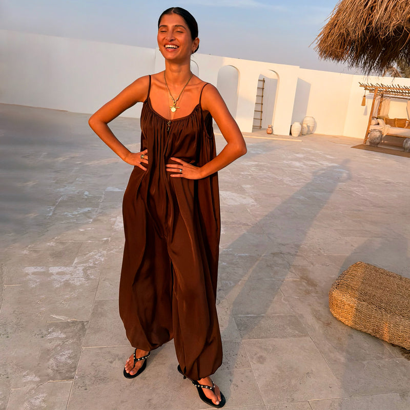 NFD Chocolate Balloon Jumpsuit with a loose draped silhouette and gathered neckline, styled in a vacation setting.