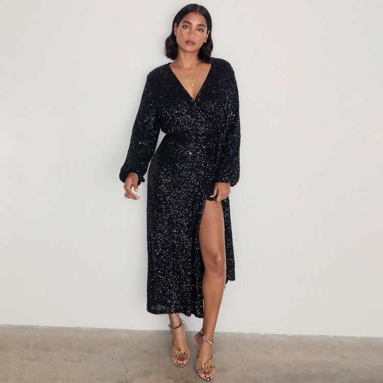 Black Sequin Kira Wrap Dress with long sleeves, a V-neckline and a leg slit, shown on a model.