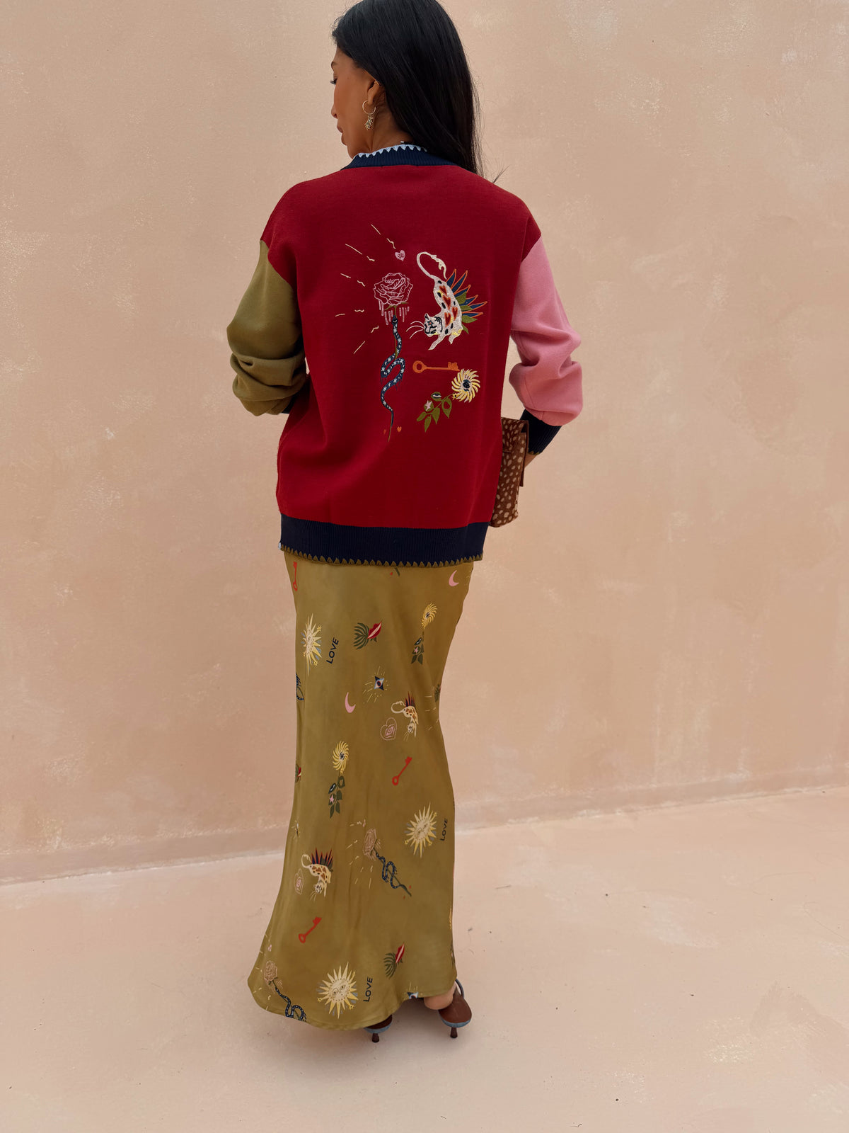 Olive Mystical Dorris Skirt with a celestial print, styled with a red color-block cardigan from behind.