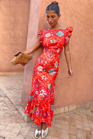 Tomato Tapestry Frida midi dress in red featuring sun motifs and ruffle sleeves, styled with gold mules.