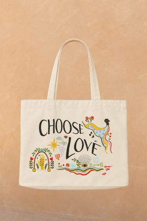 Choose Love Tote Bag in cream recycled cotton featuring colourful graphic artwork and black text against a tan wall.