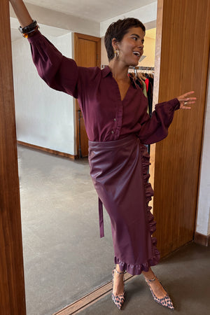 Burgundy vegan leather Jaspre wrap skirt with ruffle detailing, styled with a matching shirt and leopard print heels.