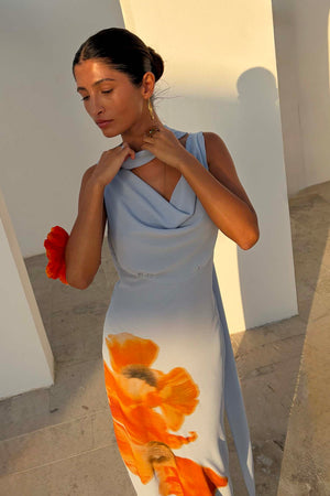 Ice Blue Floral Sophie Dress featuring a drape neckline and large orange floral print in a sunlit vacation setting.