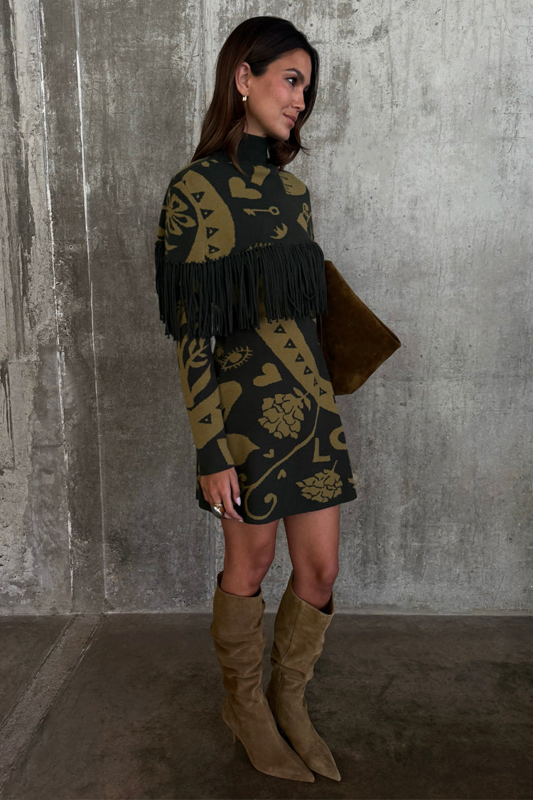 Olive Amara Knit Mini Dress featuring a fringe chest detail and gold motifs, styled with slouchy tan boots.