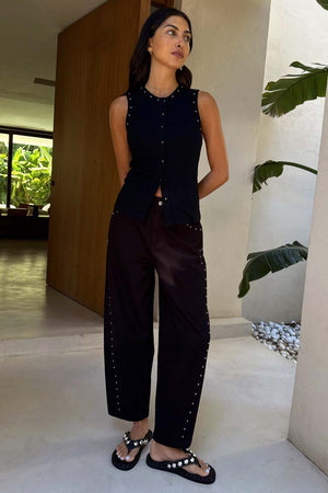Jeans Black Studded Barrel neri con borchie laterali e top smanicato coordinato su una modella.