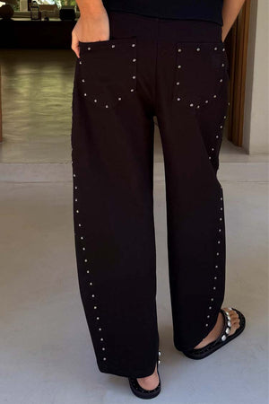 Jeans neri barrel leg con borchie argentate su lati e tasche; modella alta 170 cm in taglia 40.