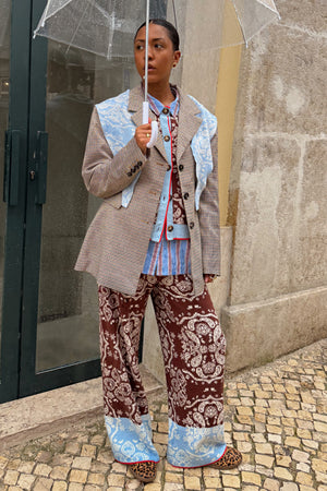 Chocolate Bandana Wide Leg Trousers in brown knit with a blue hem, styled with a layered blazer and clear umbrella.