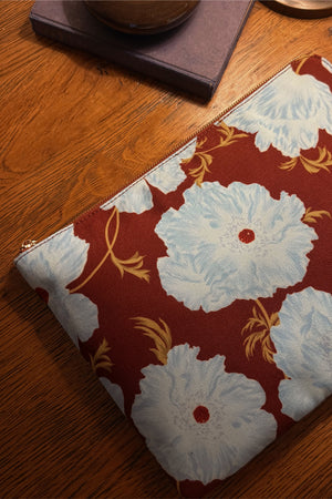 Blue and Burgundy Poppy Laptop Case featuring an in-house designed floral print and gold zip on a wooden table.