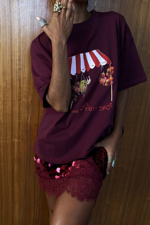 Burgundy Fruit Shop T-shirt with a relaxed fit and dropped shoulders, styled with a red sequinned lace skirt.