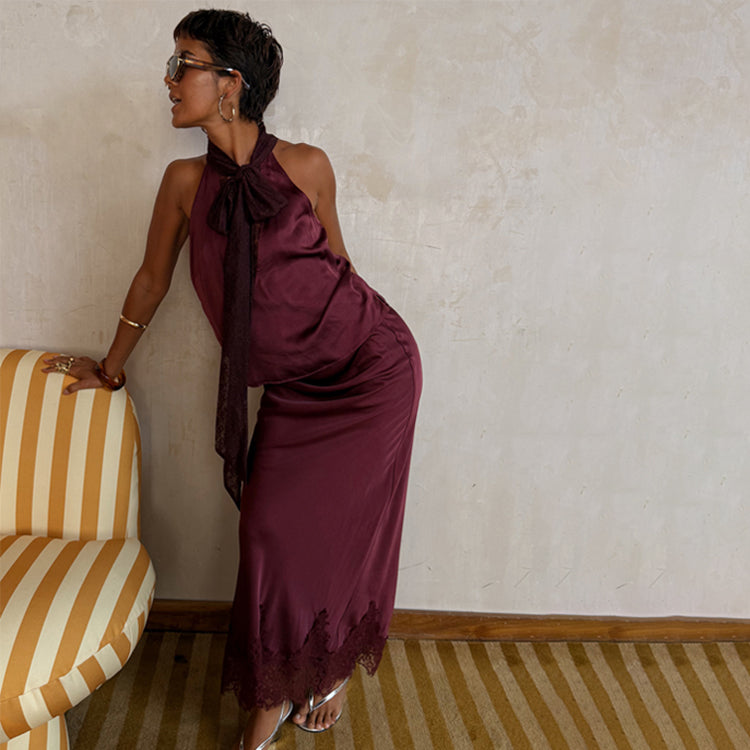 Burgundy Maeva Midi Skirt with a lace hem and matching pussybow top, worn by a model leaning against a striped chair.