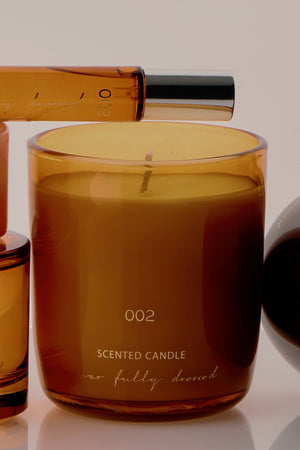 NFD Scent 002 Candle in an amber glass jar with gold lettering, paired with the matching perfume bottle.