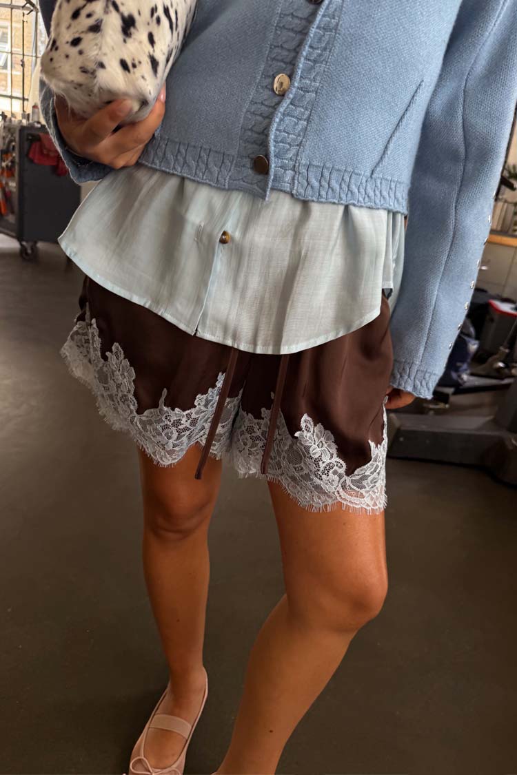 Shorts color cioccolato con pizzo azzurro abbinati a un cardigan celeste e ballerine rosa.