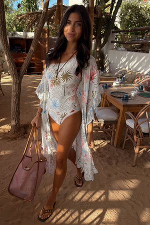 Modella alta 170 cm in taglia M con kimono Cream Palma a stampa illustrata in un resort.