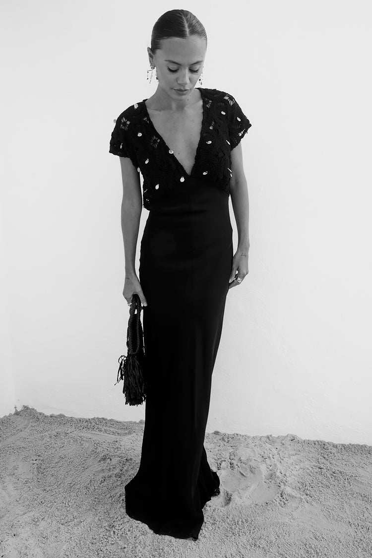 Black Crochet Shell Elodie Dress with a shell-embellished crochet bodice and satin skirt in a seaside setting.