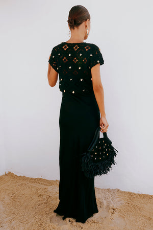 Black Crochet Shell Elodie Dress with gold shell embellishments and a satin skirt, styled with a fringed bag.
