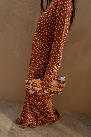 Fawn Soho Dress in brown and cream spotted satin, shown from the side with a star print clutch.
