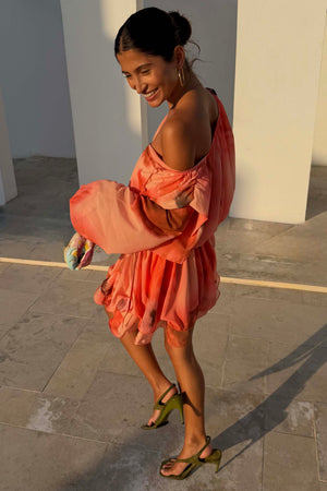 Blurred Floral Ella Mini Dress in peach orange with flute sleeves and a tiered ruffle skirt styled off the shoulder.