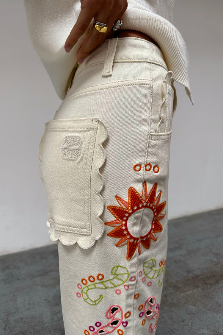 Jeans Ecru Enchanted con tasca posteriore smerlata e colorati motivi a sole ricamati.