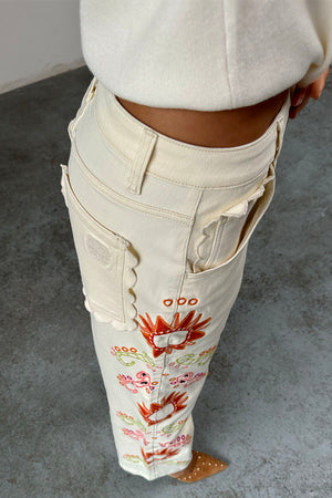 Jeans ecru Enchanted con ricami colorati e tasche posteriori con bordo a smerlo.