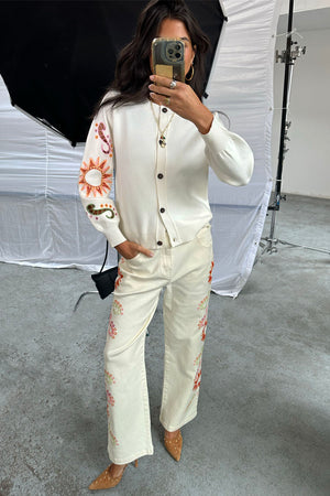 Jeans Enchanted ecru a gamba ampia con ricami colorati, mostrati in un selfie allo specchio in studio.