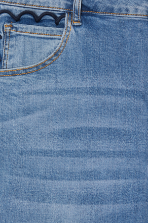 Dettaglio dei jeans flare in denim blu con bordo smerlato blu scuro sulla tasca e cuciture oro a contrasto.