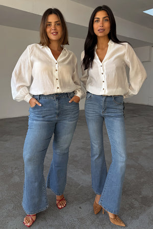 Jeans Flare Scallop in denim blu anni '70, indossati da due modelle per mostrare le taglie inclusive.