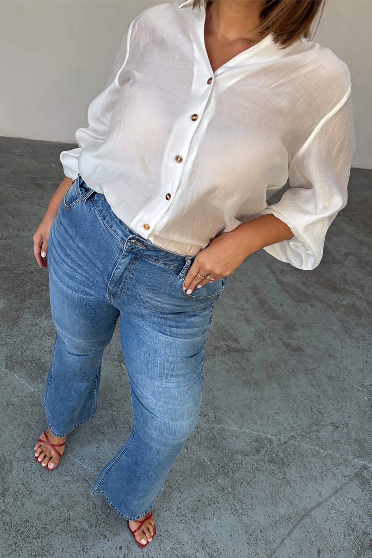 Jeans in denim blu con fondo a zampa e tasche smerlate anni '70, su una modella taglia 52.