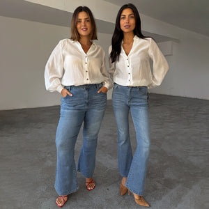 Jeans a zampa Scallop in denim blu anni '70 su due modelle per mostrare la vestibilità inclusiva.