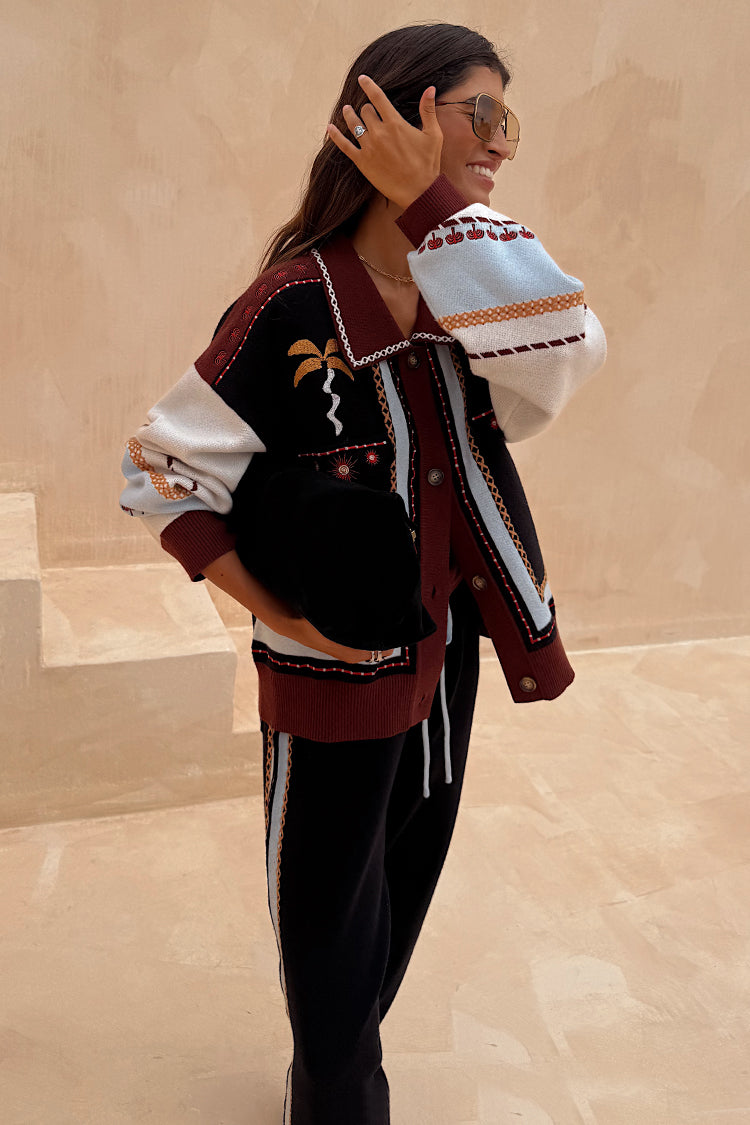 Geometric Knit Cardigan with iconic palm motifs in autumnal tones, styled with matching black joggers.