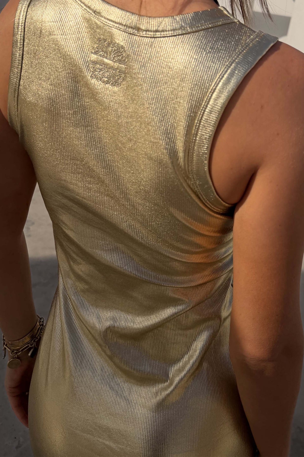 Gold Metallic Ribbed Dress detail featuring shimmering gold textured fabric and a sleeveless back design.