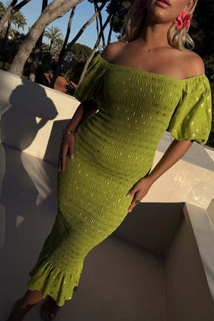 Olive Jojo Dress with gold fleck print, shirred body and puff sleeves, worn off-the-shoulder outdoors.