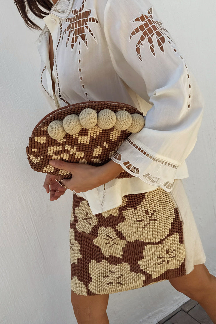 Jaden Beaded Clutch Bag with brown and cream beadwork and large baubles, styled with a white palm-cutout shirt.